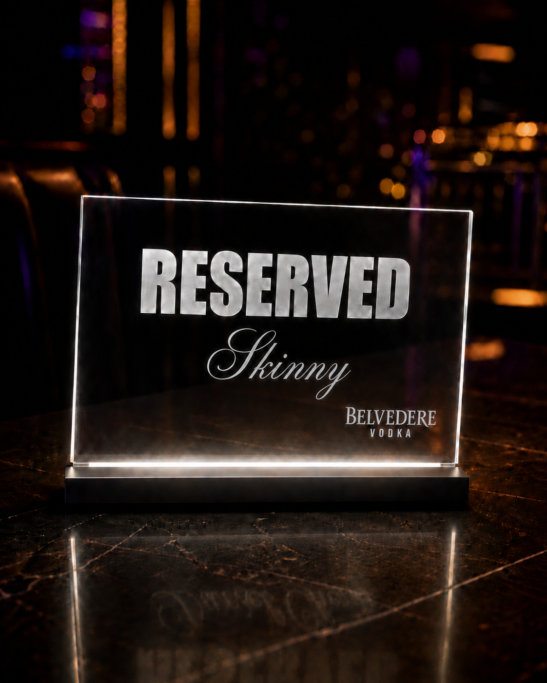 A lit crystal RESERVED table placard engraved for Skinny, with Belvedere Vodka branding